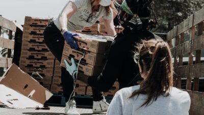 woman in white t-shirt and blue denim jeans sitting on brown cardboard box