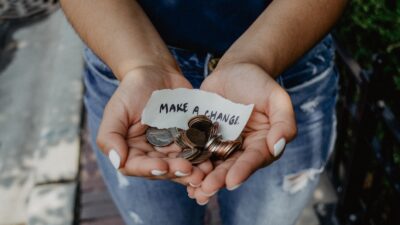 person showing both hands with make a change note and coins