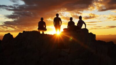 silhouette photography of four person on cliff during sunset