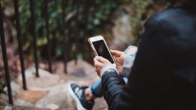 person holding white smartphone sitting on stair